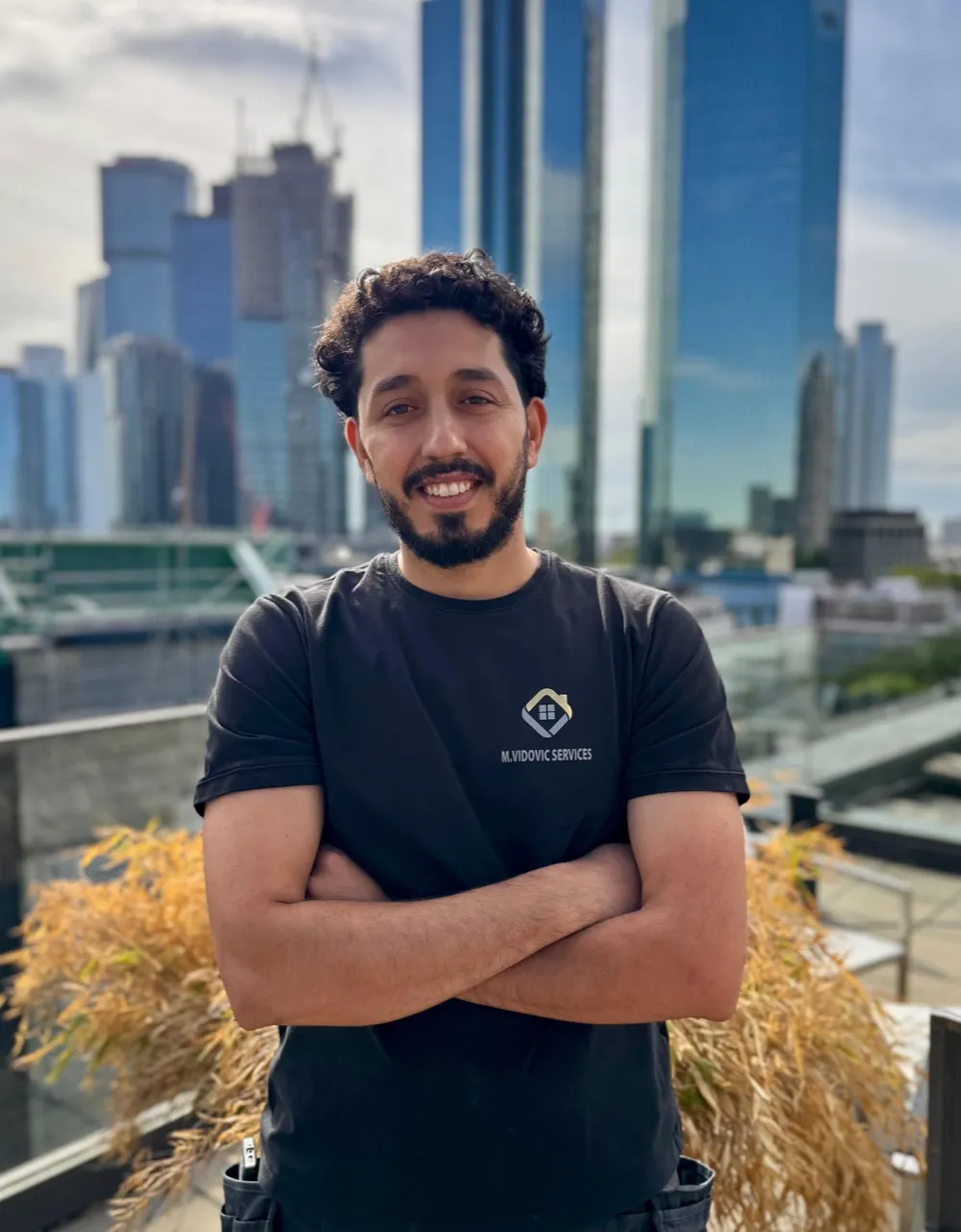 Milad Mohammadi im Firmen-Shirt von M. Vidovic Services vor der Frankfurter Skyline